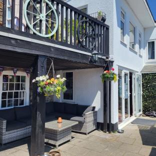 Exterior view of a pub patio with seating and hanging flower baskets.