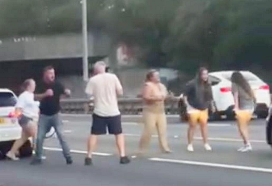 A woman was seen dragging another motorist out of their car by their hair - as six people were captured on camera having a "road rage brawl" on a motorway. The group of people can be seen throwing punches at one another before a woman drags another woman out of a car by her hair. According to a witness the fight involved occupants of a white Audi A3 and a larger black car on the M25. Two men are seen grappling and swinging wild punches at each other as stunned motorists drive past. The fight took place yesterday evening (07/09) on the southbound lanes of the motorway, near the J12 Thorpe interchange with the M3.
