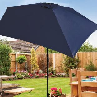 Navy blue crank and tilt parasol in a garden.