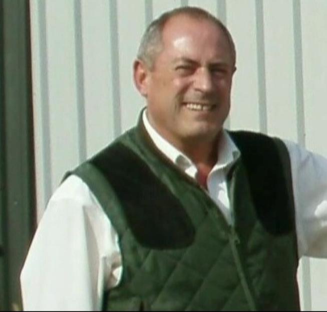Pete Bicks smiling, wearing a green vest over a white shirt.