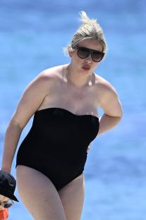 Amy Hart at the beach in a black swimsuit.
