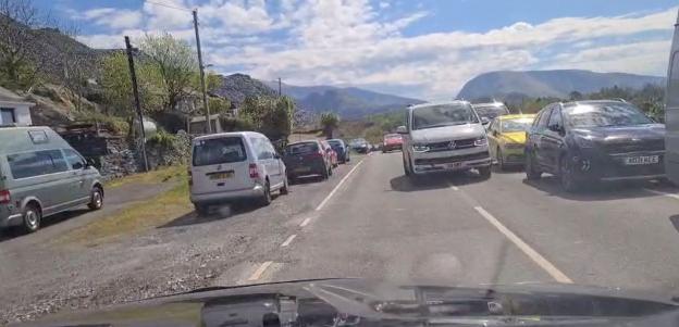 Double-parked cars lining a road near a quarry.