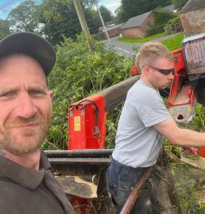 Two men using a wood chipper.
