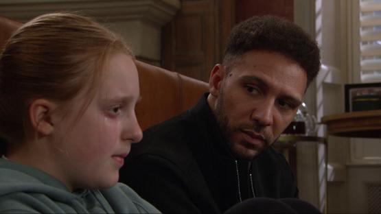 A man and a crying girl sit together.