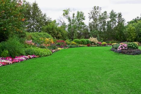 Landscaped formal garden with colorful flowers and green lawn.