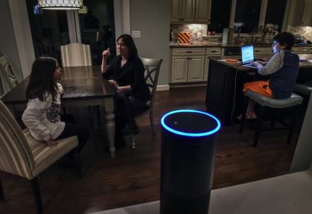 A woman and her two children using an Amazon Alexa device in their home.
