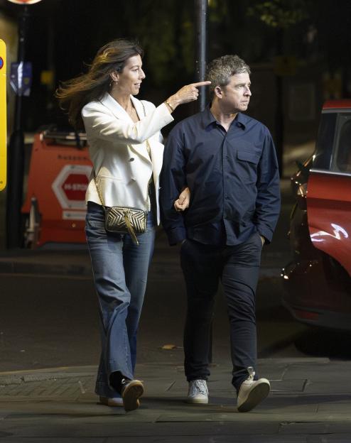 Noel Gallagher and Sally Mash walking together at night.