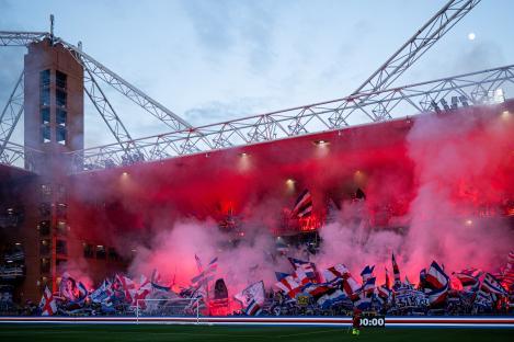 Sampdoria fans lighting flares and waving flags in a stadium.