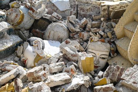 Damaged Buddha statues buried in rubble after an earthquake.