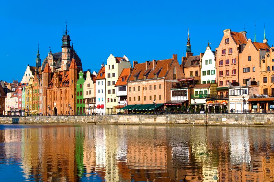 Waterfront buildings in Gdansk, Poland, with reflections in the water.