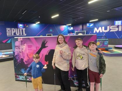 A woman and three boys at a Tech Putt mini golf course.
