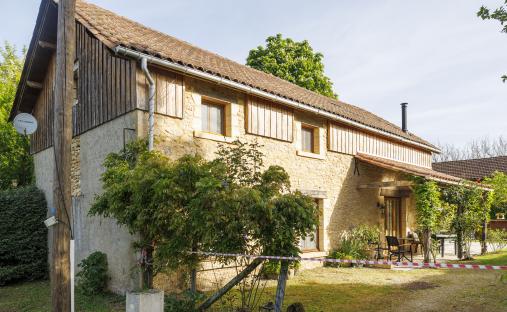 Stone house with patio, outdoor furniture, and a wooden pool.