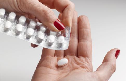 A hand removing a pill from a blister pack.