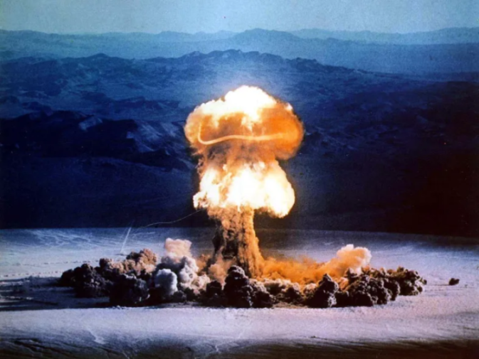 An atomic bomb blast forming a mushroom cloud over a desert landscape.