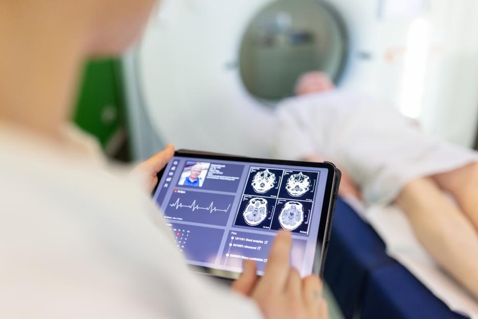 Doctor reviewing brain scan images on a tablet.