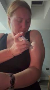 Woman injecting herself in the arm.