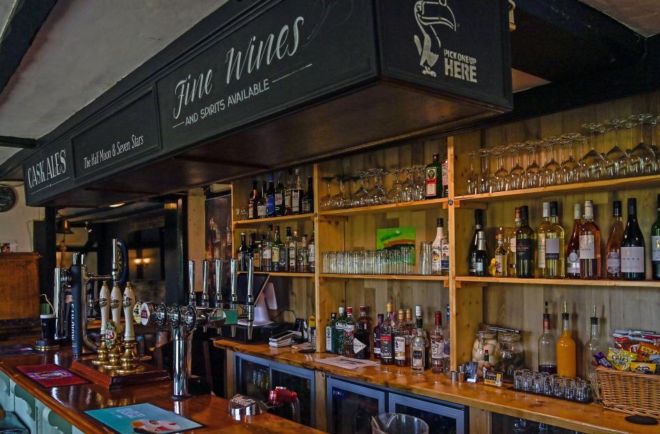 The Half Moon & Seven Stars pub bar, showing the bar top, beer taps, shelves of liquor, and glasses.