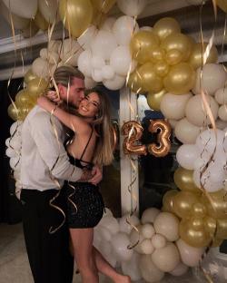 a man and woman are hugging in front of balloons with the number 23 on them