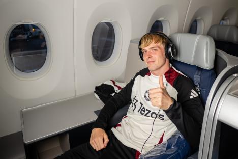 Toby Collyer of Manchester United giving a thumbs up while seated on a plane.