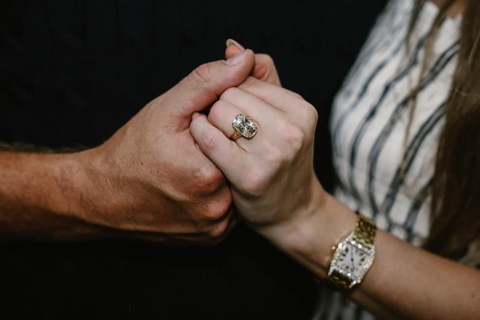 Close-up of Taylor Swift and Travis Kelce's hands clasped together, showcasing her engagement ring.