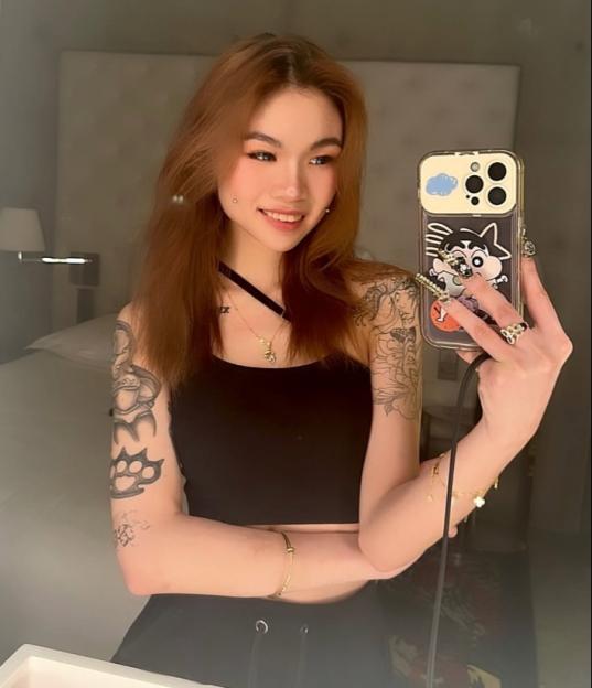 Selfie of a young woman with tattoos and a phone.