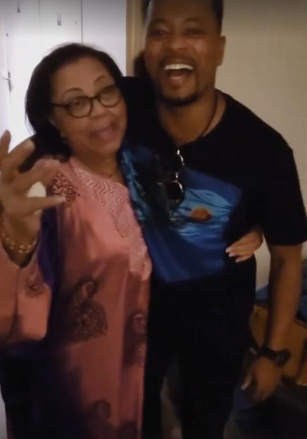 Man with a dark shirt hugging a woman with glasses and a pink top.