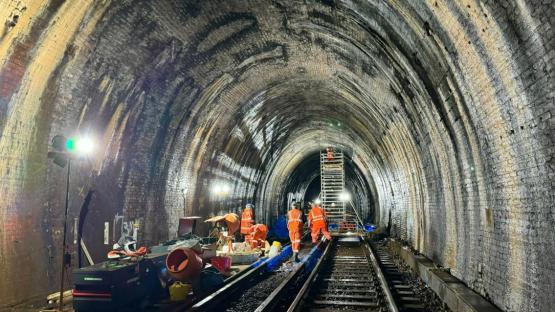 Workers repairing a brick railway tunnel.
