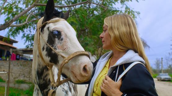 Chloe Sevigny with a horse in *Magic Farm*.