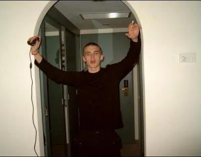 Man holding a game controller in a doorway.