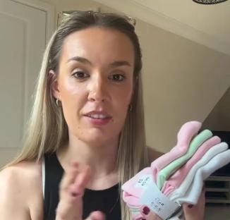 Woman holding up a pack of children's socks.