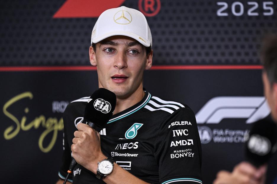 Mercedes' British driver George Russell speaks into a microphone at a press conference.
