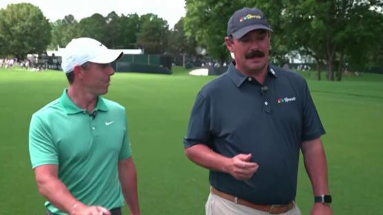 Two men walking and talking on a golf course.