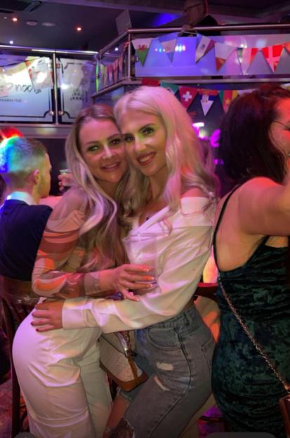 Photo of two women hugging in a bar.