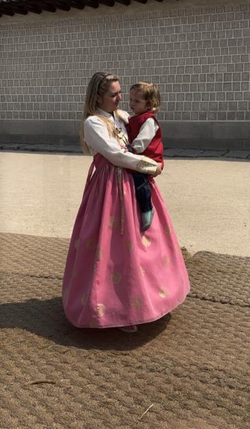 Woman in pink Hanbok holding a toddler in South Korea.