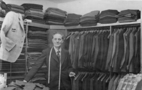 Black and white photo of a tailor in his shop.