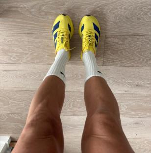 Person's legs wearing yellow athletic shoes and white socks.
