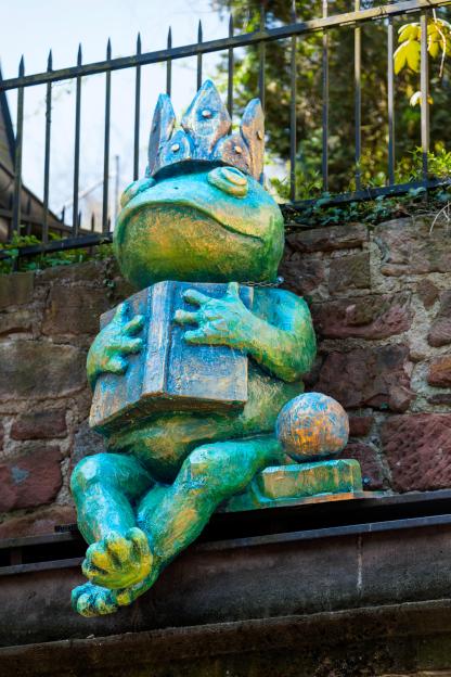 Sculpture of a frog king reading a book.