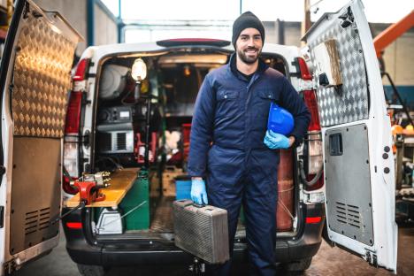 Mechanic standing in his van with tools.