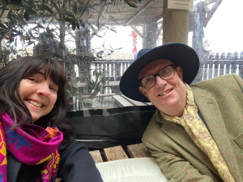 Patrick Howard and his wife Laura smiling at an outdoor cafe.