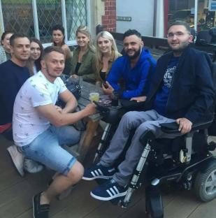 Group of friends sitting outside, one in a wheelchair.