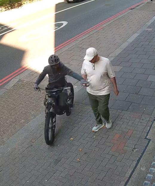 CCTV image of a thief on an electric bike stealing a phone from a pedestrian.