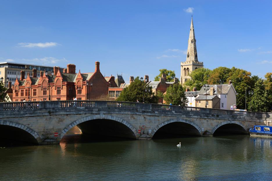 A bridge crossing the Great River Ouse, Bedford, with the Church of St Paul and buildings in the background.