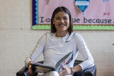 Emma Raducanu reading a book at a primary school.
