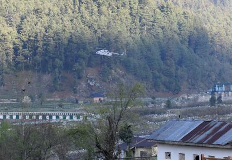 Military helicopter flying over a forested hillside in Anantnag, Jammu and Kashmir, India.