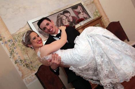 A man holding his wife in a wedding dress.