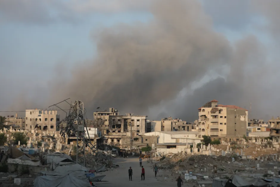 Smoke rises over a war-torn city.