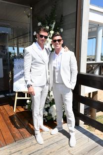 Two men in white suits and sunglasses at a vow renewal ceremony.