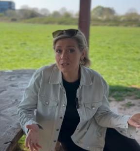 Woman in light jacket speaking outdoors.