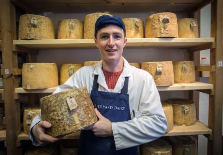 Young man holding cheese at a cheese shop.