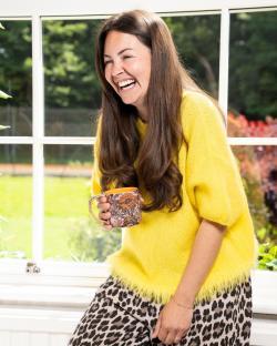 Lacey Turner laughing while holding a mug.